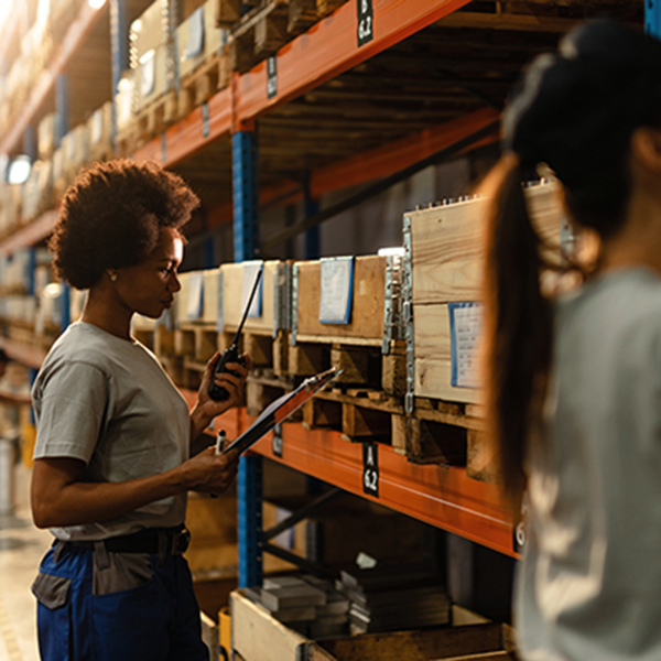 Warehouse associate scanning bin labels and recording counts on a clipboard at a pallet rack